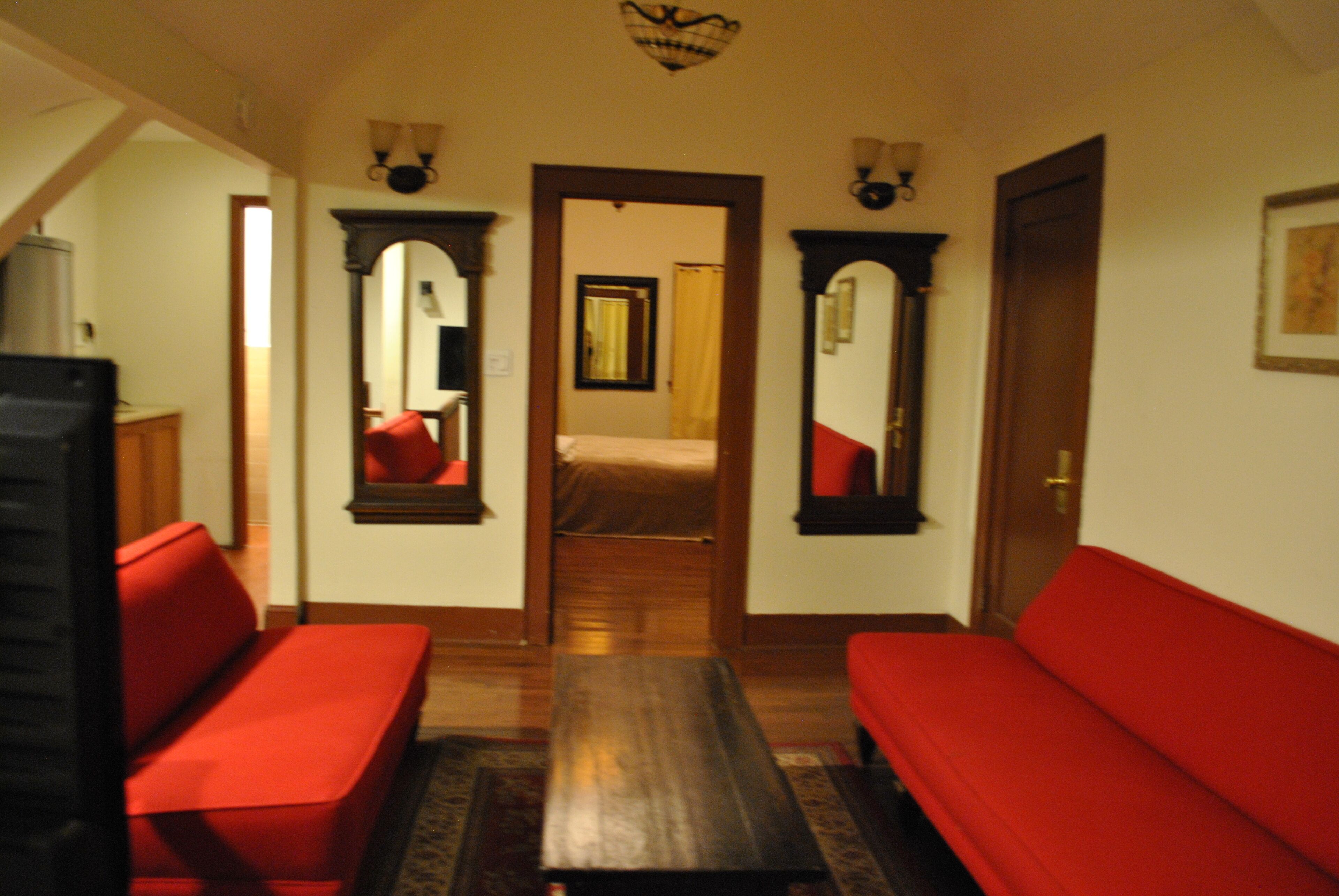 A hallway with red sofas, a wooden bench, and a mirror on the walls.