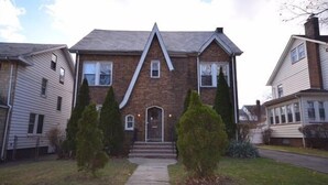 A two-story house with a brick facade, a gabled roof, and a front porch with steps leading to a door. - Newark Hansbury Multi Level House (Newark)