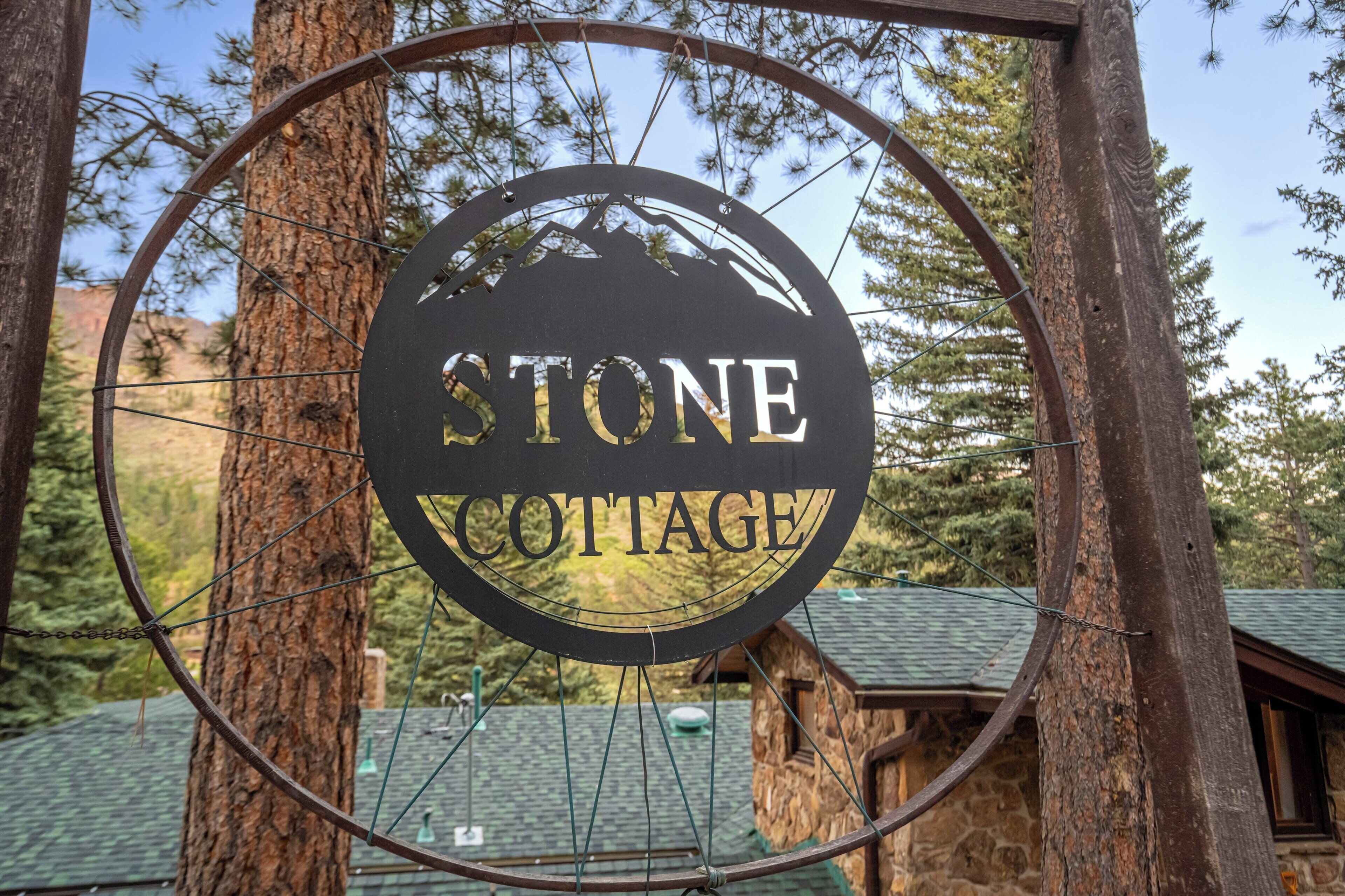 A circular sign with the words 'STONE COTTAGE' in the center, surrounded by a metal frame.
