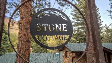 A circular sign with the words 'STONE COTTAGE' in the center, surrounded by a metal frame.