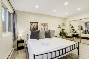 Ein Schlafzimmer mit einem Bett, einem Nachttisch, einer Lampe, einem Spiegel und Wandbildern.