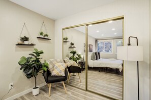 Une chambre à coucher moderne avec un grand miroir, un lit, une chaise et des plantes en pot.