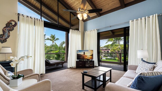 A spacious living room with a large TV, comfortable seating, and a view of the outdoors.