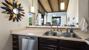 A modern kitchen with a stainless steel sink, a dishwasher, and dark wooden cabinets.