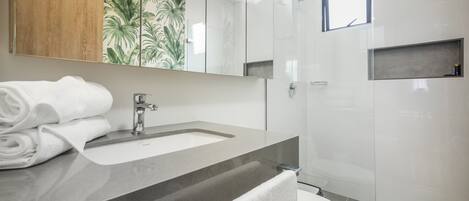 A modern bathroom with a sink, mirror, and toilet.