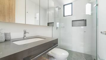 A modern bathroom with a large mirror, a sink, and a toilet.