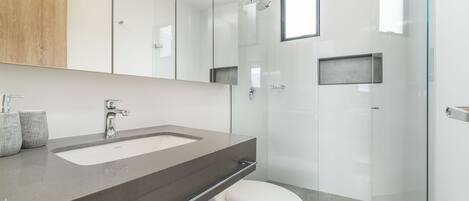 A modern bathroom with a large mirror, a sink, and a toilet.