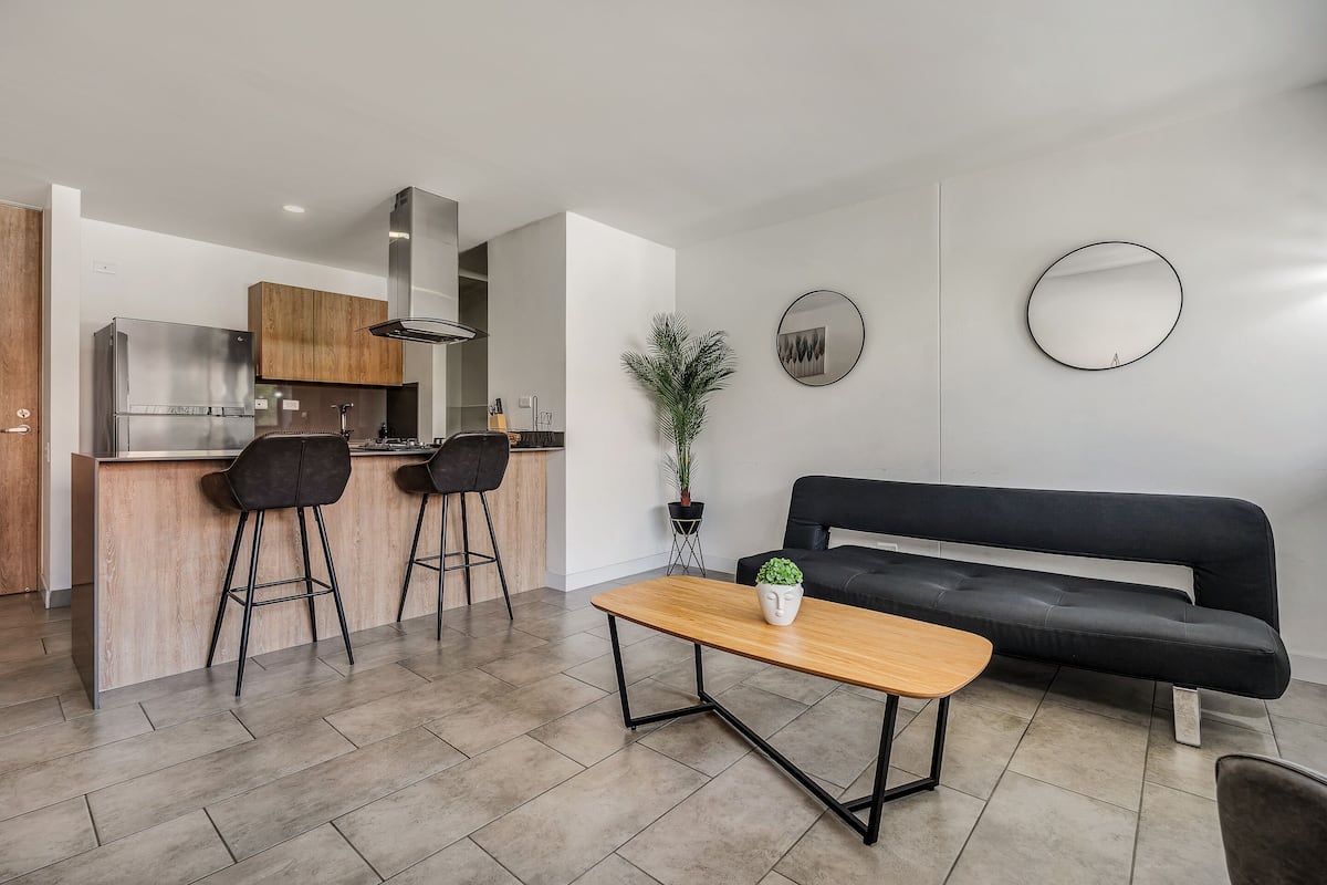 Una cocina moderna con estufa empotrada, armarios de madera y un taburete negro.