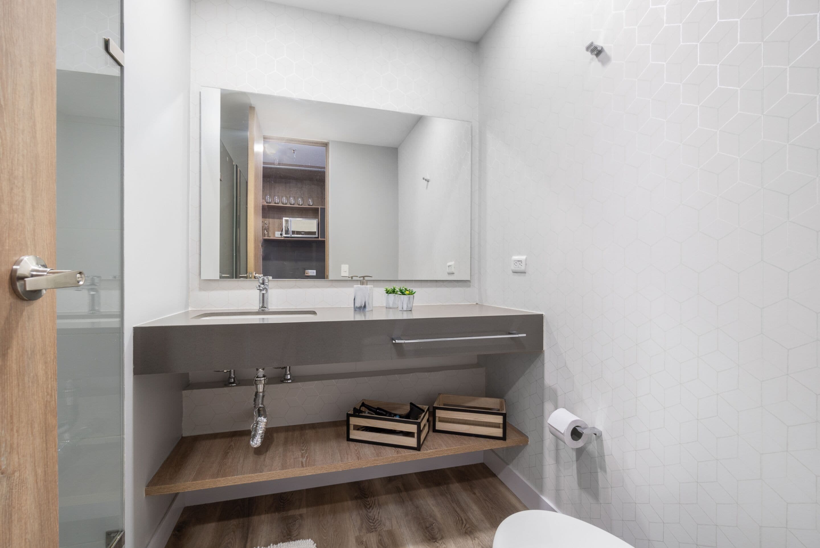 A modern bathroom with a wooden vanity, a large mirror, and a toilet.