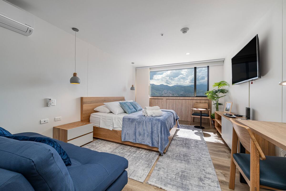 Un dormitorio moderno con cama, mesitas de noche, escritorio y televisión.