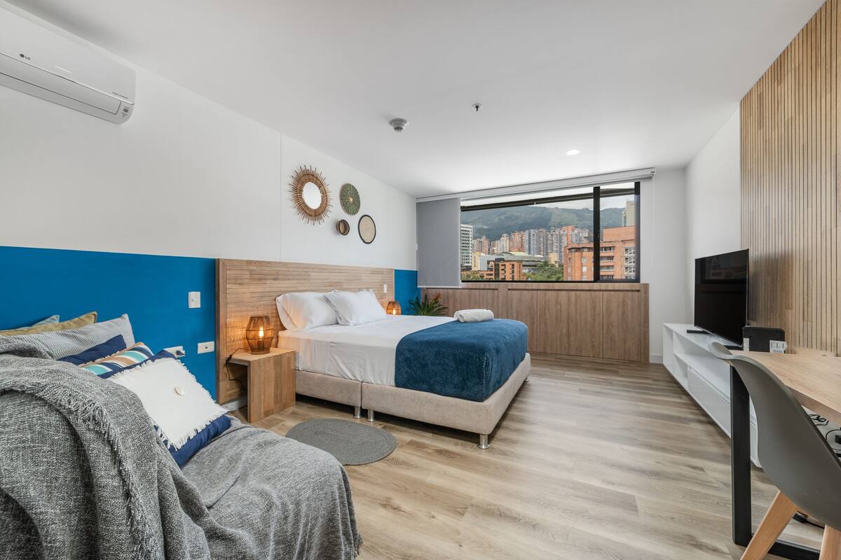 Una habitación de hotel moderna con cama, mesita de noche y escritorio con silla.