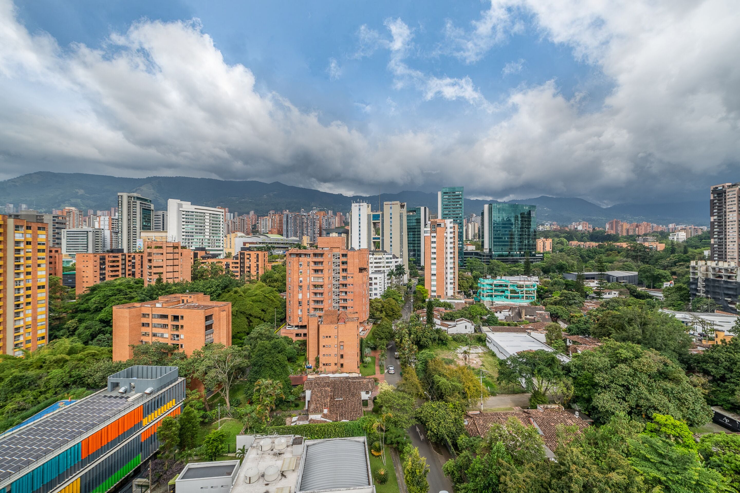 A cityscape with high-rise buildings, a train, and mountains in the background.