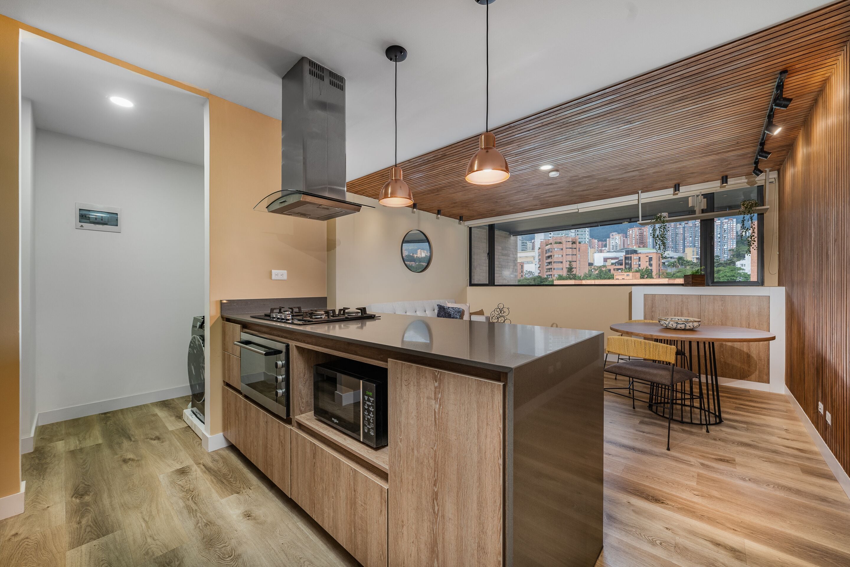 A modern kitchen with a central island, built-in oven, microwave, and stainless steel range hood.