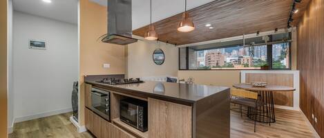 A modern kitchen with a central island, built-in oven, microwave, and stainless steel range hood.