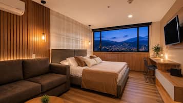 A modern bedroom with a bed, a sofa, a desk, and a large window with a city view.