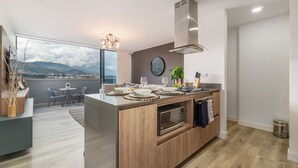 A modern kitchen with a central island, a dining area with a view, and a large window.