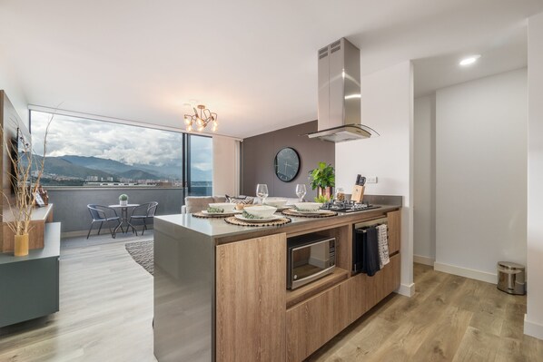 Een moderne keuken met een centraal eiland, een eethoek met uitzicht en een groot raam.