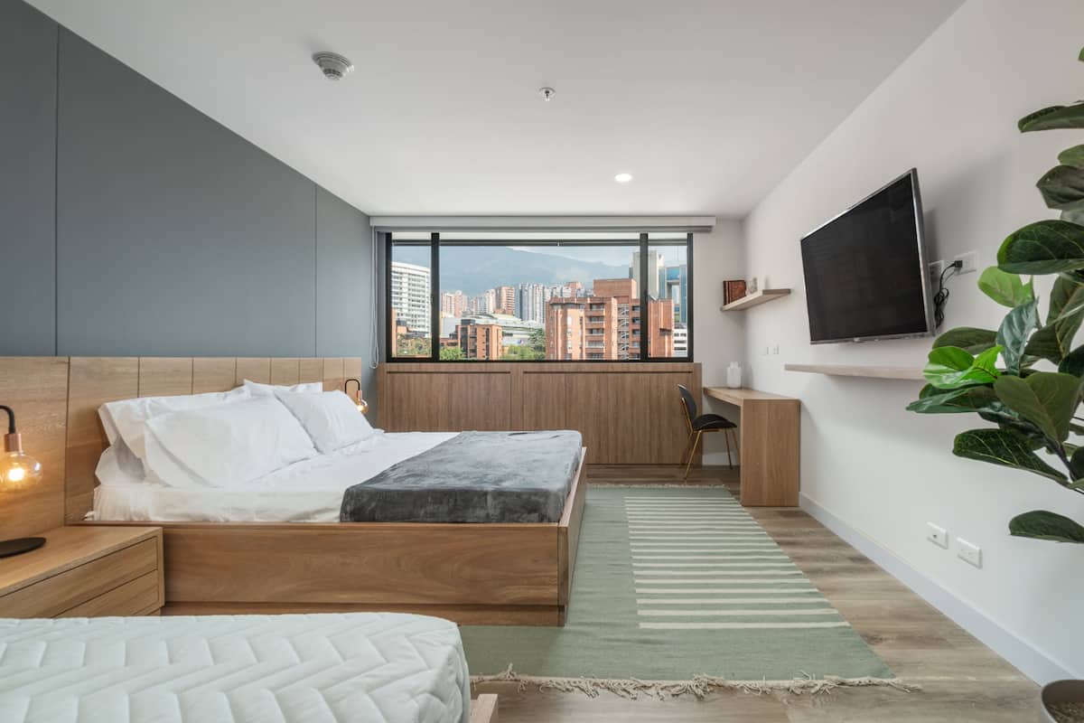Un dormitorio moderno con una cama grande, un escritorio y un televisor.