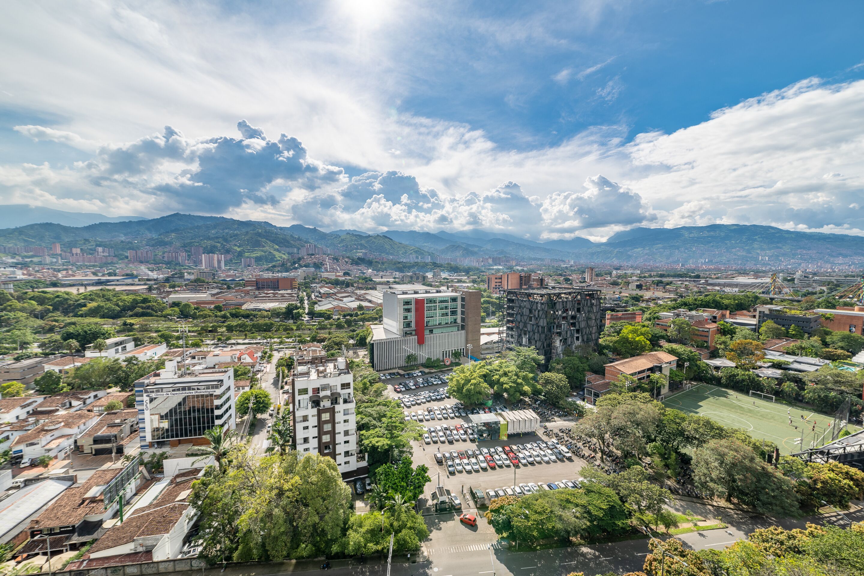 Una vista aerea di un paesaggio urbano con edifici, un parcheggio e un campo da calcio.