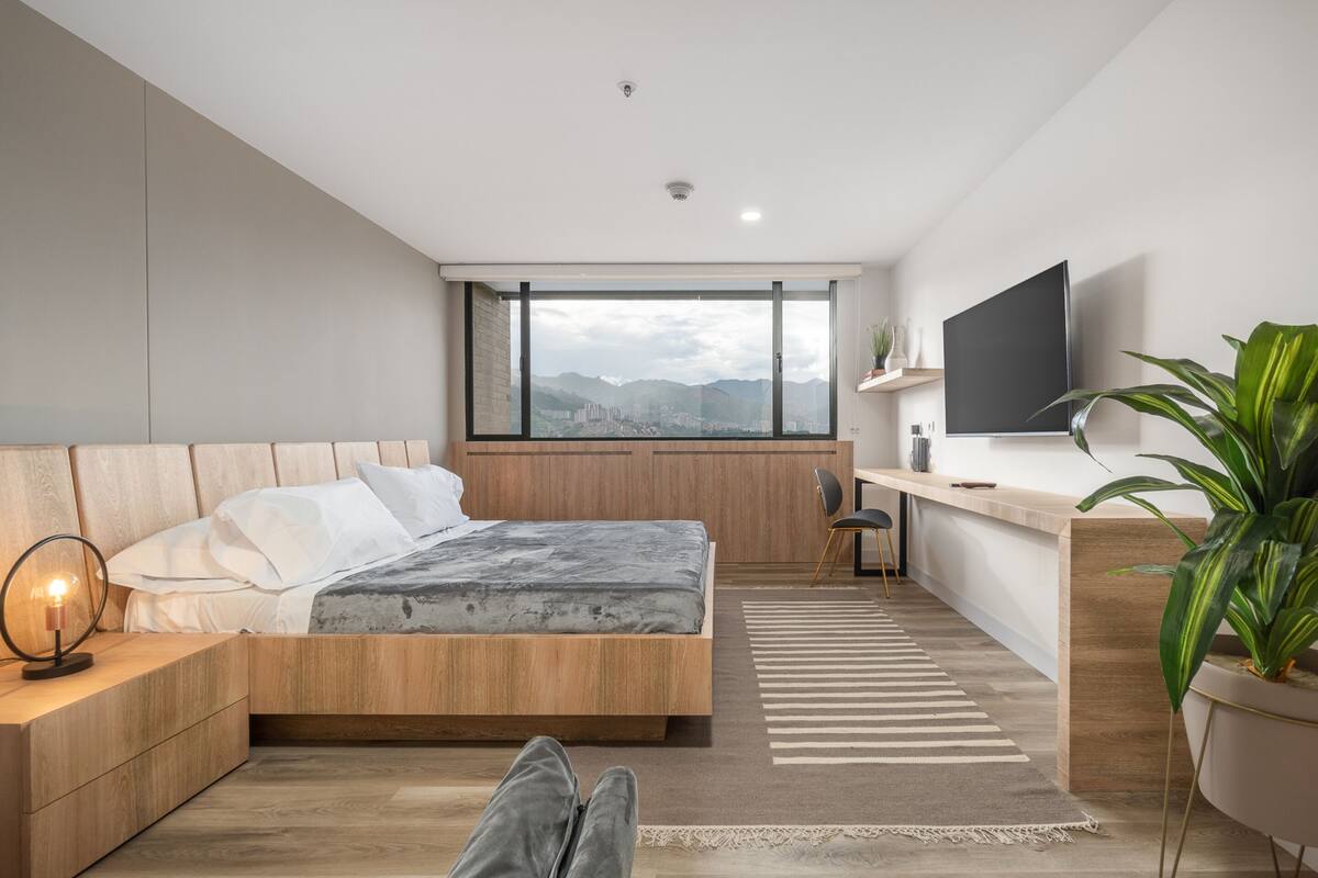 Un dormitorio moderno con cama, mesita de noche y escritorio con silla.
