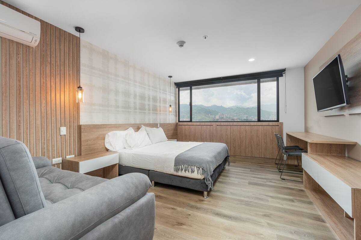 Un dormitorio moderno con una cama grande, un escritorio, una silla y un televisor.
