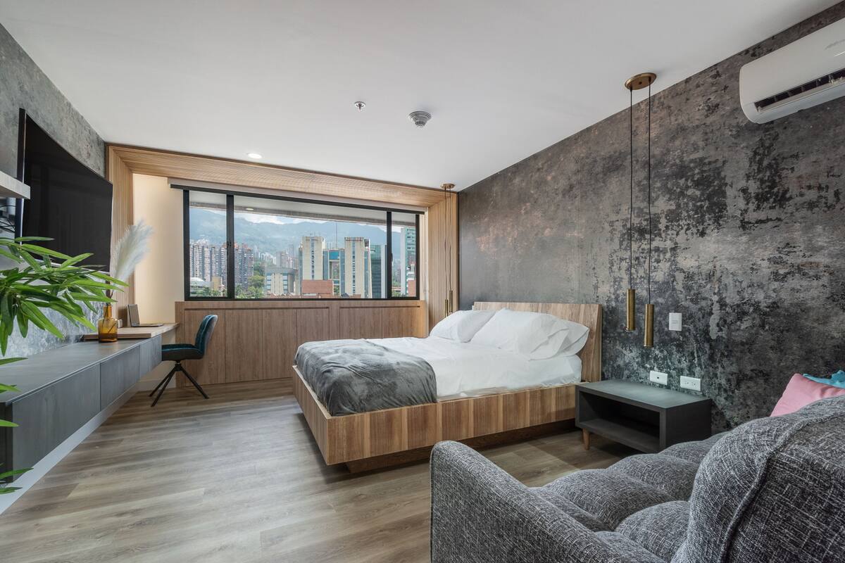 Un dormitorio moderno con un ventanal grande, una cama, un escritorio y una silla.