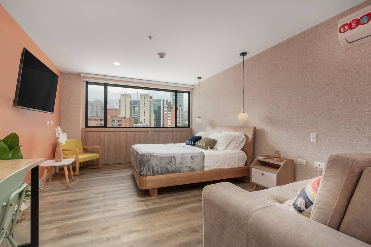 Una habitación de hotel moderna con una cama grande, un escritorio, una silla y un sofá.