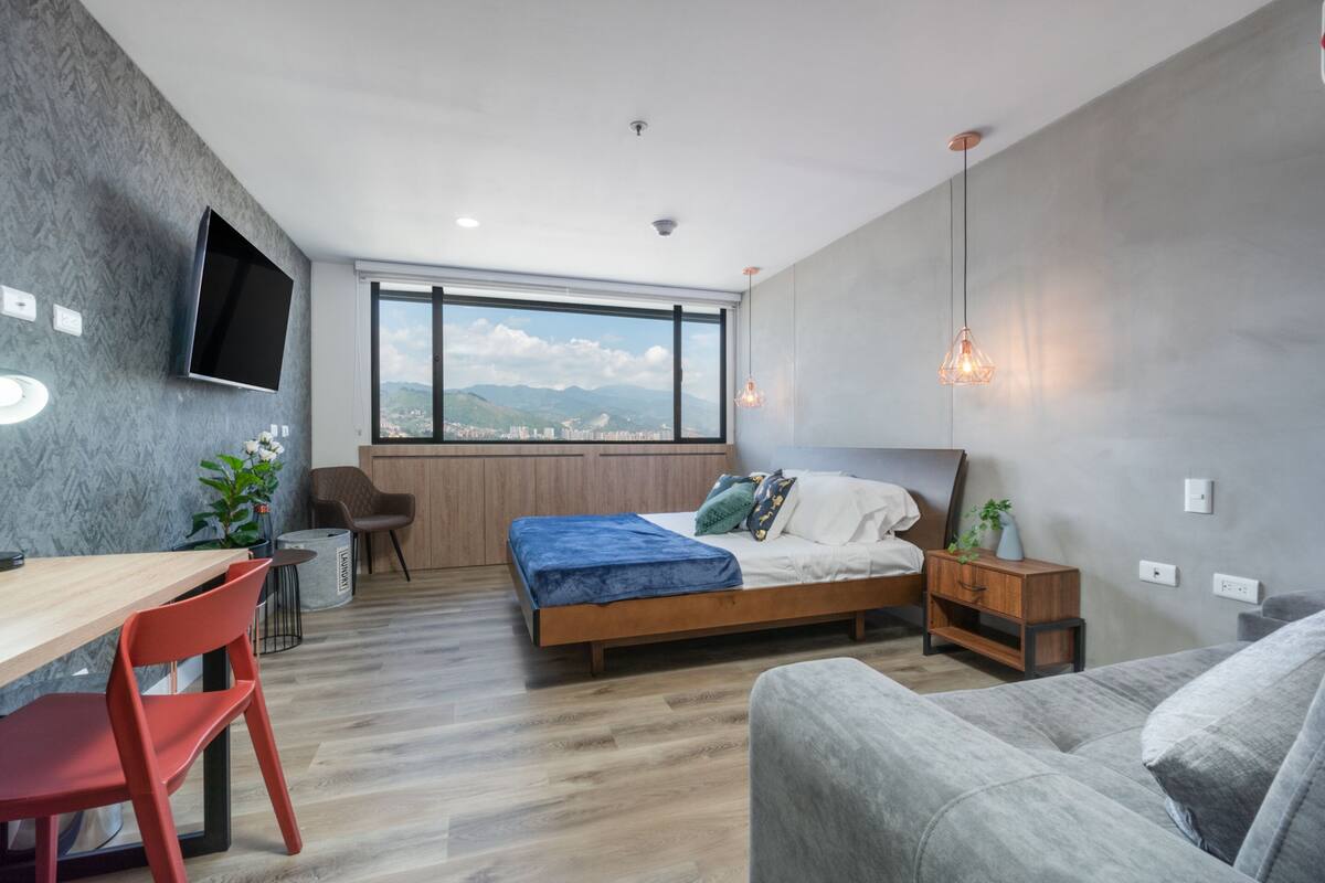 Un dormitorio moderno con cama, escritorio, silla y sofá.