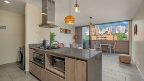 A modern kitchen with a central island, built-in oven, and a large window offering a city view.