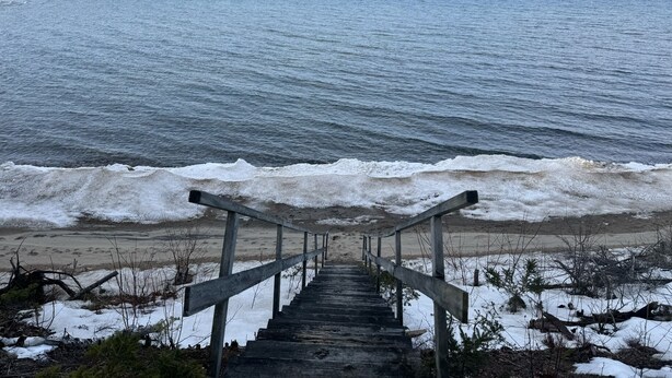 Una escalera de madera que conduce a una playa, con olas rompiendo sobre la orilla.