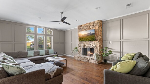A spacious living room with a sectional sofa, a fireplace, and large windows. - Luxury Home Sleeps 20 with Heated Pool & Billiard (Dallas)