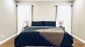 A bedroom with a large bed, two bedside tables, and white curtains. - Luxury Home Sleeps 20 with Heated Pool & Billiard (Dallas)