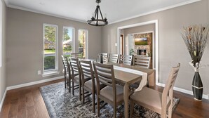 A dining area with a wooden table and chairs, a chandelier, and a view of the outdoors. - Luxury Home Sleeps 20 with Heated Pool & Billiard (Dallas)