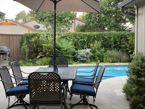 Une terrasse extérieure avec une table et des chaises, un barbecue et une piscine.
