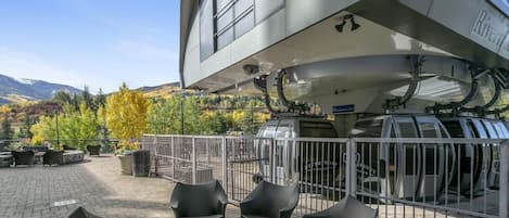 Un bâtiment moderne doté d’un espace extérieur aménagé, abrité et agrémenté de meubles en osier, offrant une vue sur les montagnes.