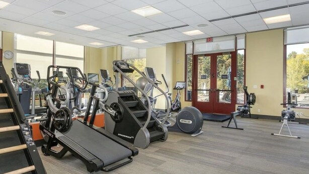 Ein Fitnessstudio mit Laufbändern, Crosstrainern und Gewichtsgeräten.