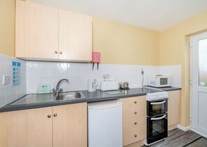 Una cocina compacta equipada con lavabo, tostadora, hervidor, microondas y horno.
