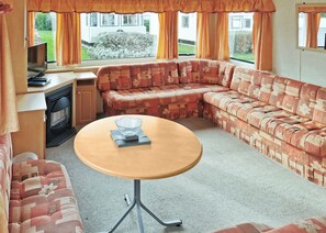 A cozy RV interior with a sofa, a table, a TV, and a fireplace.