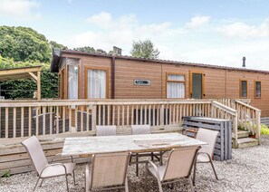 Une cabane en bois dotée d’une terrasse, de meubles de jardin et d’une enseigne indiquant « Aspen Lodge ».