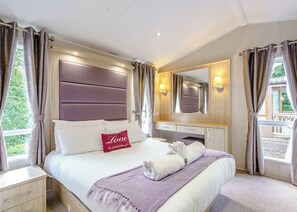 Une chambre à coucher avec un lit, une table de chevet, une commode, un miroir et des rideaux.