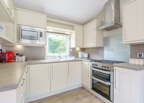 A modern kitchen with white cabinets, a stainless steel stove, and a microwave. - 2 bedroom accommodation in Calthwaite, Nr Penrith (Calthwaite, Nr Penrith)