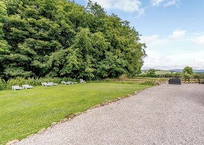 A grassy area with white lounge chairs and a gravel path.