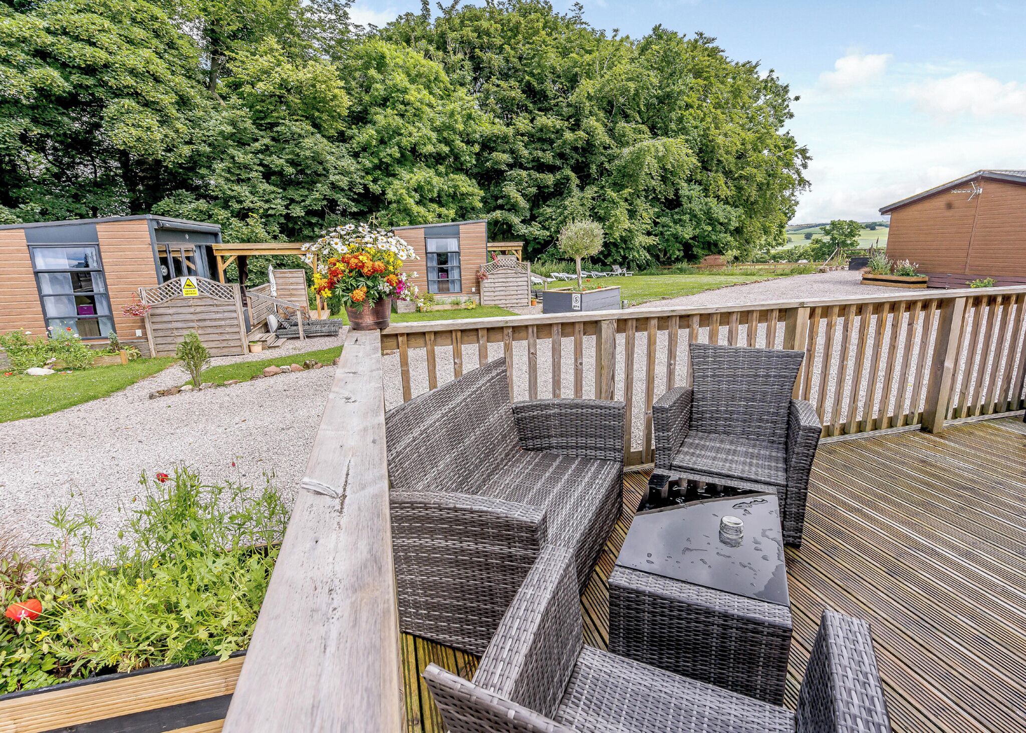 A wooden deck with wicker furniture and a flower arrangement.