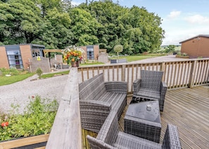 A wooden deck with wicker furniture and a flower arrangement.