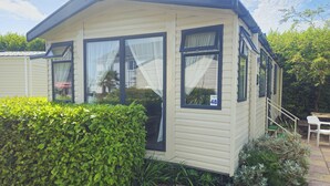 A mobile home with a number '48' on the window, a small porch, and a staircase leading to the entrance.