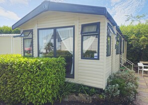 A mobile home with a number '48' on the window, a small porch, and a staircase leading to the entrance. - Modern caravan with one double and one twin. (Saundersfoot)
