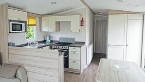 A compact kitchen with a microwave, stove, and sink, a small dining area, and a door leading to another room.