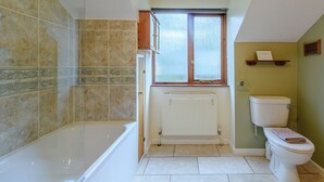 Un baño con bañera, inodoro y ventana.