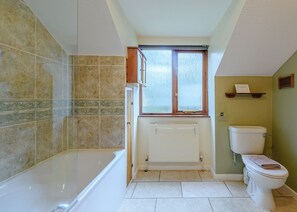 A bathroom with a bathtub, toilet, and window.