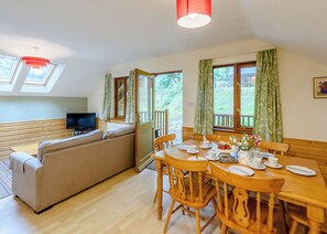 A cozy living room with a sofa, a dining table set for four, and a television.